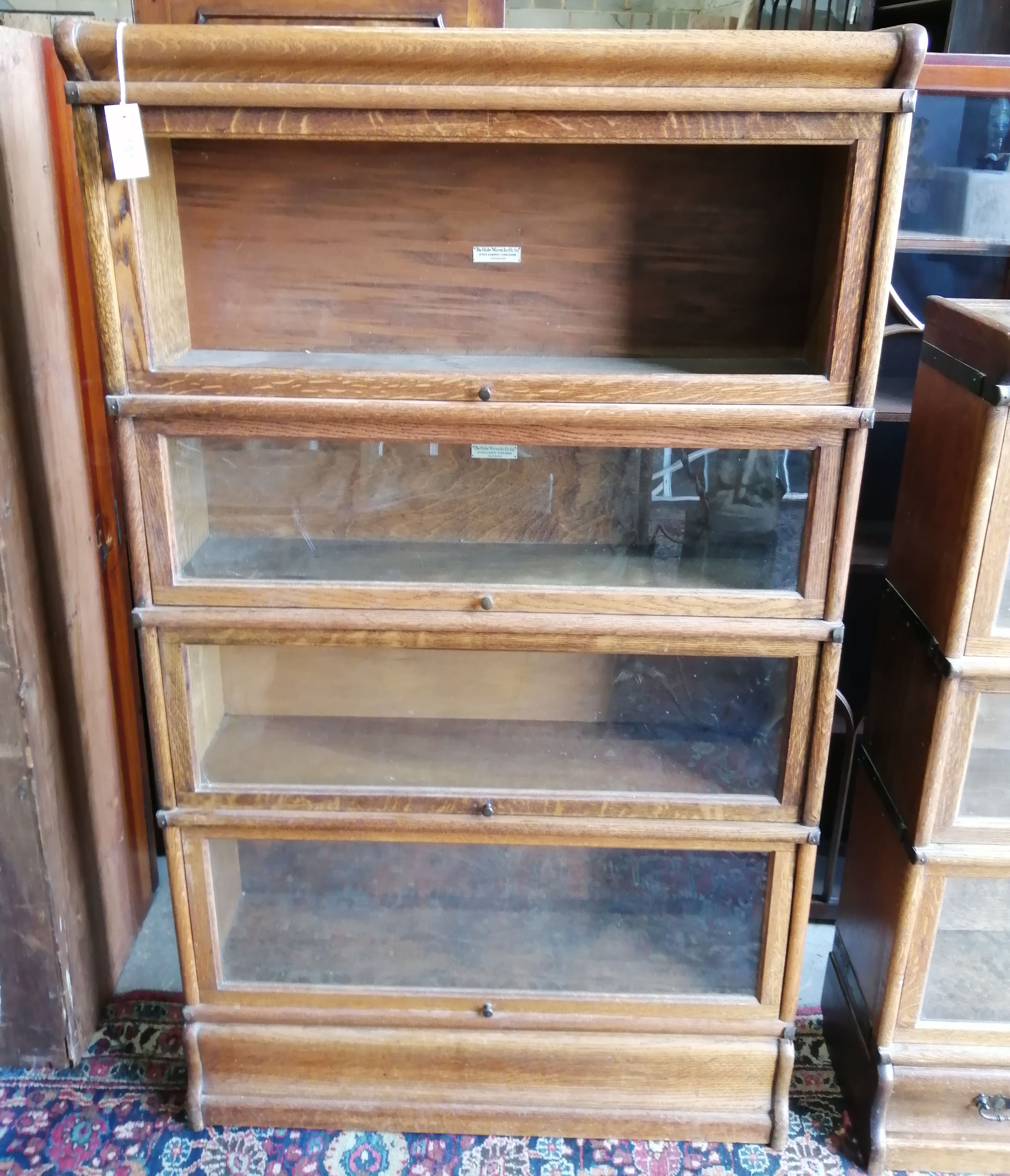 A Globe Wernicke oak 4 section bookcase, one door lacks glass, width 86cm, depth 27cm, height 148 cm.